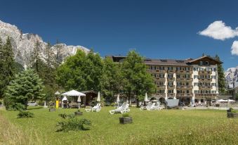 a large hotel surrounded by a grassy field , with several people sitting on chairs in the grass at Hotel Villa Argentina
