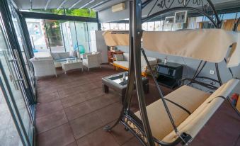 a patio area with a metal swing hanging from the ceiling , surrounded by various chairs and tables at Arya Otel