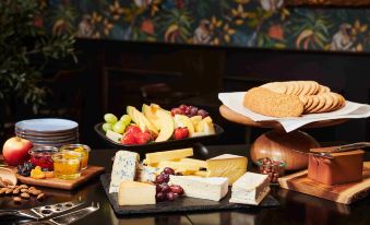 a dining table with a variety of food items , including cheese , bread , grapes , and fruit at Thon Hotel Hallingdal