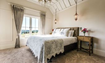 a large bed with a white comforter and pillows is in a room with two windows at Mudbrick Cottages