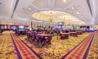 a large casino with multiple tables and chairs , as well as televisions on the walls at Casino Queen Hotel
