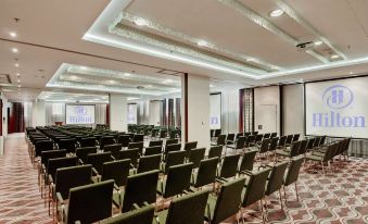 a large conference room with rows of chairs arranged in a semicircle , and a podium at the front of the room at Hilton Gdansk