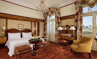 a luxurious hotel room with a large bed , a desk , and a chandelier , all decorated in a luxurious style at Hotel Bristol, a Luxury Collection Hotel, Vienna
