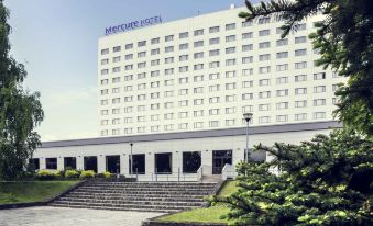 a large white hotel building surrounded by trees and grass , with stairs leading up to the entrance at Hotel Mercure Gdynia Centrum