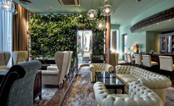 a well - decorated living room with various seating options , including couches and chairs , under a large window at Hotel Continental