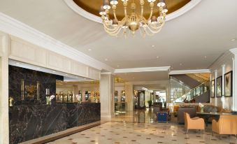 a luxurious hotel lobby with a marble floor , a gold chandelier hanging from the ceiling , and a marble reception desk at Garden City Hotel
