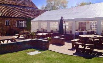 a large white tent is set up on a grassy area with several tables and benches arranged around it at St Quintin Arms