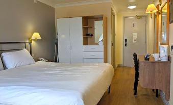 a clean and well - organized hotel room with a bed , desk , and a white wardrobe , all neatly arranged at 247Hotel.Com