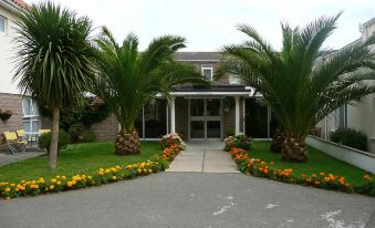 a large , white house with a front door and surrounded by lush green grass and palm trees at Beachcombers Hotel