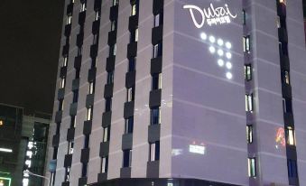 "a tall building with a large led sign that reads "" daiva "" is lit up at night" at Dubai Hotel