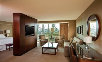 a living room with a couch , chairs , and a tv is shown with a view of the outside at Sheraton Valley Forge King of Prussia
