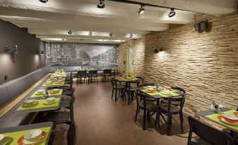 a restaurant with a stone wall , wooden tables and chairs , and a black and white mural on the wall at Nova Hotel