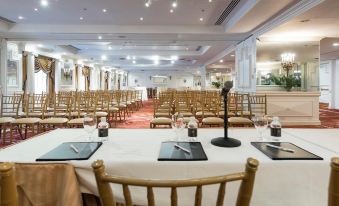 a large dining room set up for a formal event , with multiple tables and chairs arranged in rows at Garden City Hotel