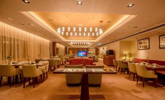 a large , well - lit dining room with multiple tables and chairs , as well as a tv mounted on the wall at Transcorp Hilton Abuja