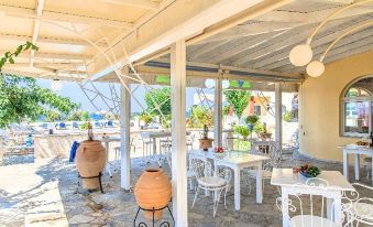 a white table and chairs are set up under a covered patio with large vases at Palladion