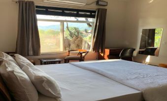 a large bed with white sheets and pillows is in a room with a window at The Sojourn