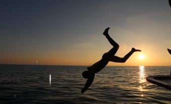 a man is diving into the ocean at sunset , with his hands in the air at Liberty Guesthouse Maldives