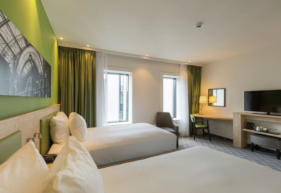 a modern hotel room with two beds , a desk , and large windows , all decorated in white and green colors at Hampton by Hilton Antwerp Central Station