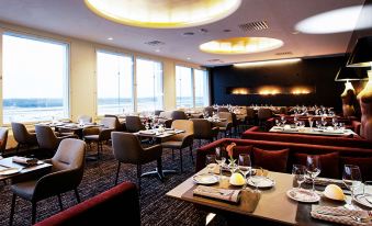 a large dining room with numerous tables and chairs arranged for a group of people to enjoy a meal at Clarion Hotel Arlanda Airport Terminal