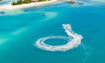 a breathtaking aerial view of a tropical island with a jet ski in the center and clear blue water surrounding it at Lux* South Ari Atoll