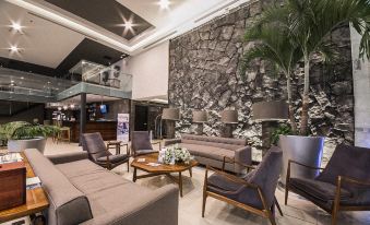 a modern living room with a gray stone wall , wooden coffee table , and multiple couches at Four Points by Sheraton Veracruz