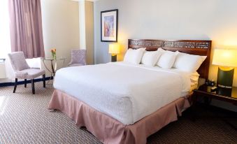 a large bed with white linens and a pink skirt is in a hotel room at Rodd Grand Yarmouth