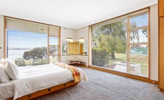 a bedroom with a large bed , wooden furniture , and a window overlooking a golf course at Riverfront Motel & Villas