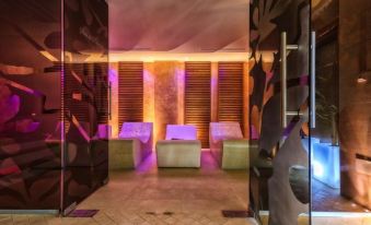 a modern spa room with three couches and a purple light , creating a relaxing atmosphere at Hotel Roman by Dumbrava Business Resort