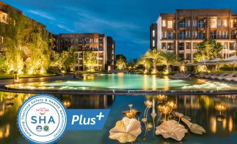 a large pool with a flower arrangement in the center and buildings surrounding it at night at Divalux Resort and Spa Bangkok, Suvarnabhumi Airport-Free Shuttle