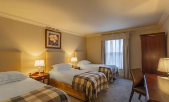 a hotel room with three beds , two of which are twin beds and one is a double bed at Bunratty Castle Hotel