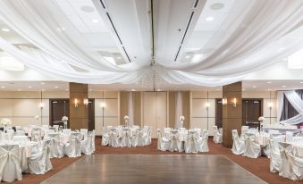 a large room with white tables and chairs set up for a formal event , possibly a wedding reception at Four Points by Sheraton Winnipeg South