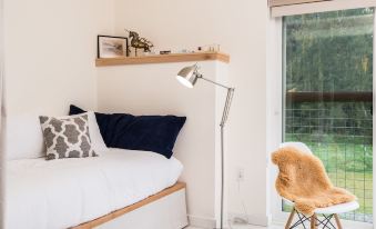 a cozy bedroom with a bed , a chair , and a window overlooking a grassy field at Lodges on Vashon