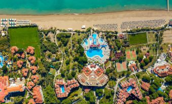 an aerial view of a resort with multiple buildings , a swimming pool , and palm trees near the beach at Aquaworld Belek