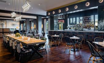 a modern restaurant with wooden floors , black tables , and chairs , and a bar in the background at Crowne Plaza North Augusta
