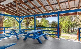 a wooden shelter with blue benches , providing shade for people sitting and enjoying the outdoors at Discovery Parks - Jindabyne