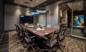 a conference room with a long wooden table surrounded by chairs , and a tv mounted on the wall at The Explorer Hotel