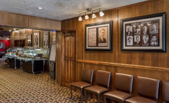a wooden reception area with leather chairs and a row of framed pictures on the wall at Best Western Dunmar Inn