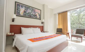 a large bed with white sheets and a colorful runner is in a hotel room at Ubud Hotel & Cottages