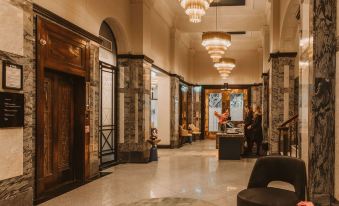 a grand hotel lobby with marble floors , wooden columns , and ornate chandeliers , as well as people standing at reception desks at DoubleTree by Hilton Wellington