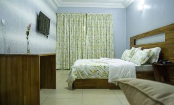 a clean and well - organized bedroom with a comfortable bed , a tv mounted on the wall , and a dresser at Hotel Lewi