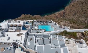 aerial view of a white building with a swimming pool , surrounded by blue water and mountains at Belvedere Suites