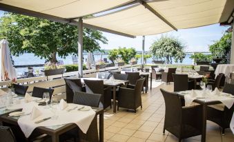 an outdoor dining area at a restaurant , with tables and chairs set up for guests to enjoy their meal at Seehotel Leoni