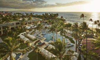aerial view of a resort with a large pool surrounded by palm trees , chairs , and lounge chairs at Four Seasons Resort Maui at Wailea