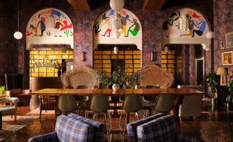 a modern , stylish bar with colorful murals and checkered chairs , set against a backdrop of wooden beams and archways at Graduate Berkeley