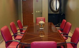 a conference room with a wooden table surrounded by red chairs and a vase on the table at Holiday Inn Carbondale-Conference Center