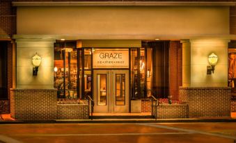 "the exterior of a restaurant named "" graze "" with brick walls , lit windows , and a sign above the entrance" at Winston-Salem Marriott