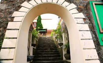 a staircase leading up to a building with a brick wall and an archway , surrounded by greenery at Cay Thong Hotel