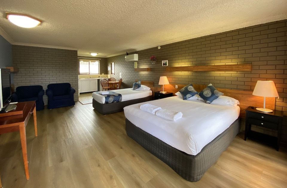 a hotel room with two beds , one on the left and one on the right side of the room at Tumut Valley Motel
