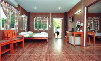 a bedroom with a brick wall and wooden floor , featuring a bed , chair , desk , and tv at I Din Lake View Resort Nakhon Nayok