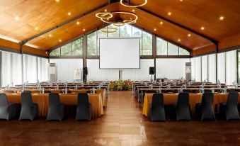 a large room with rows of chairs and tables set up for an event , possibly a conference or a wedding at Horison Green Forest Bandung